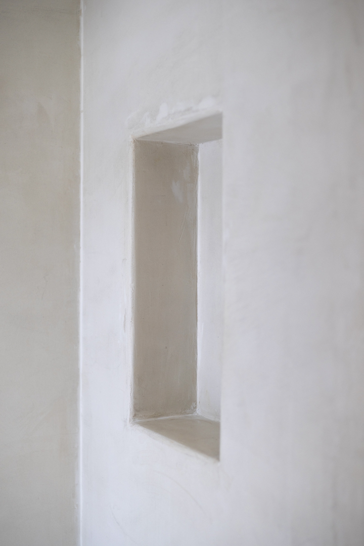Detail of a rectangular niche in a smooth textured white wall. Natural lighting.