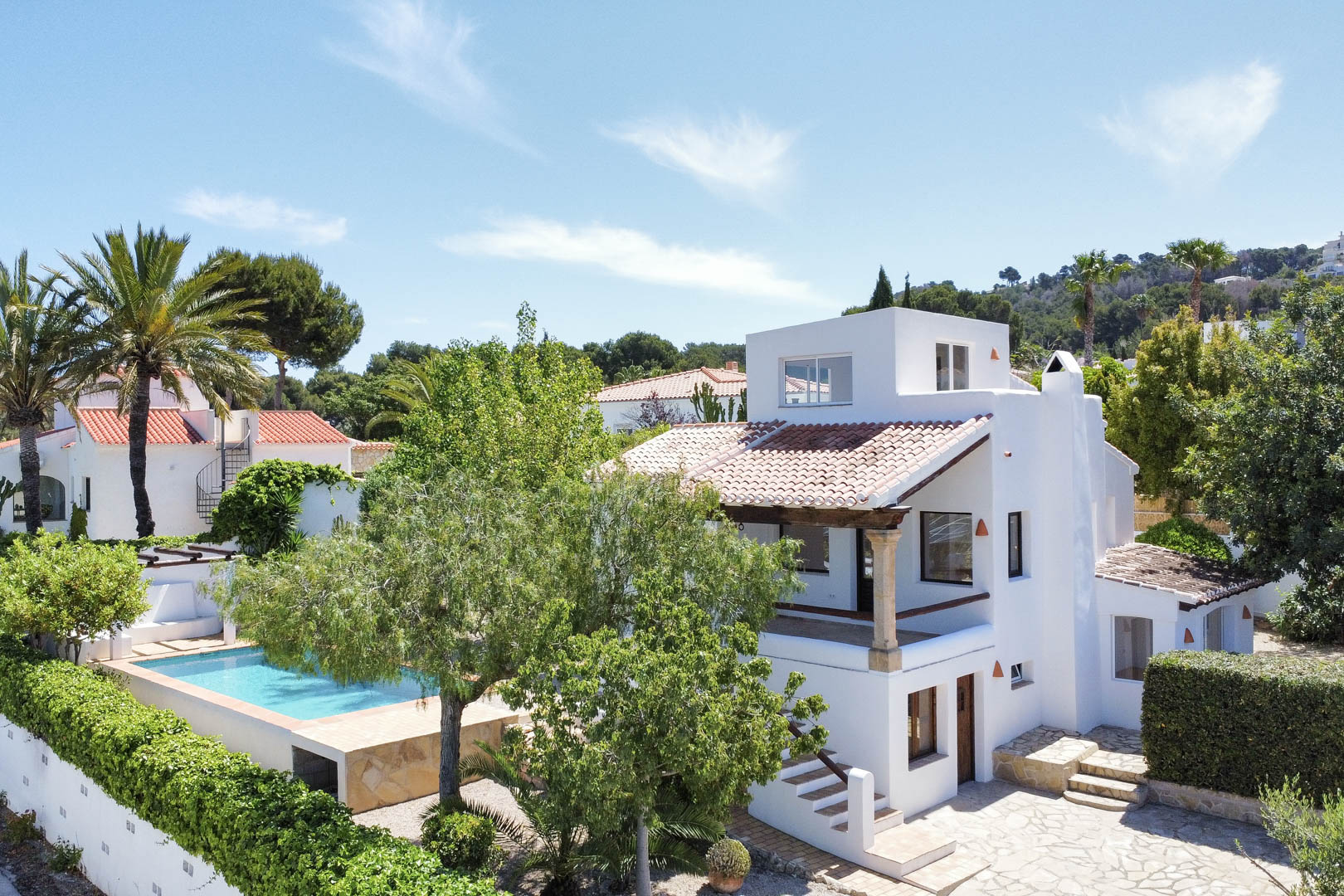Elevated view of the white villa with pool, garden, and red tile roof in Jávea.
