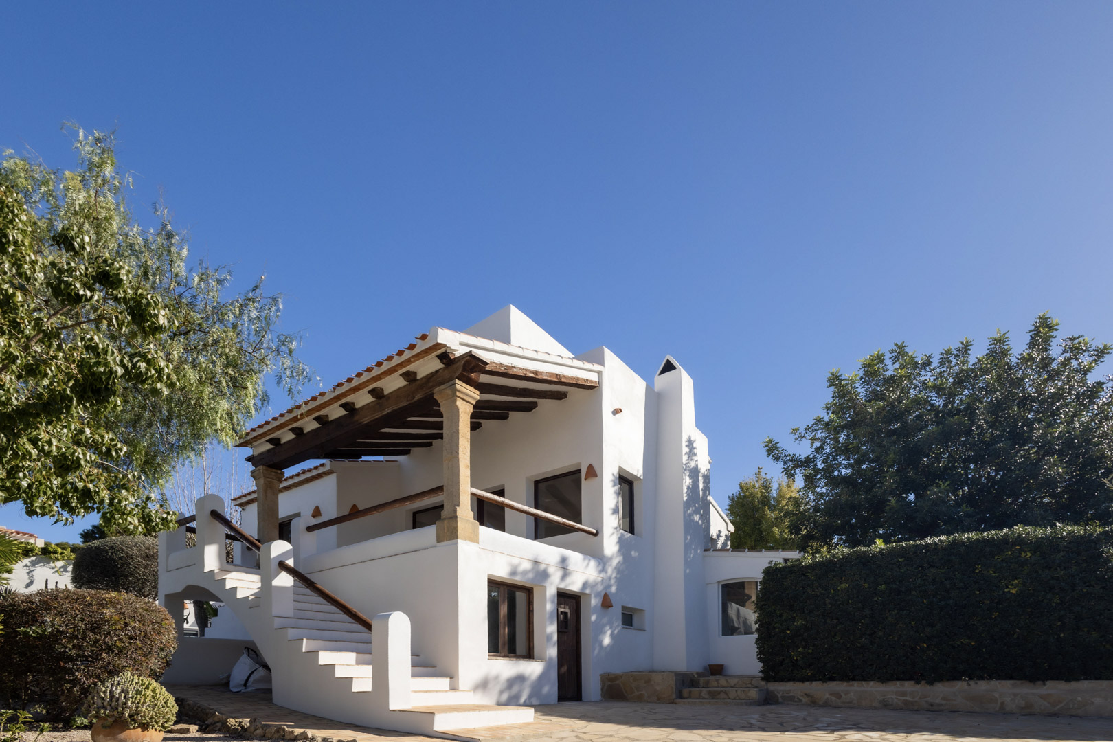 Exterior view of the renovated villa, highlighting the traditional Spanish architecture and covered terrace with wooden beams.