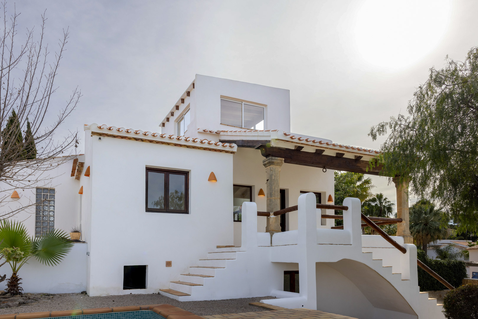 Exterior view of the villa showcasing the main entrance with access stairs and Mediterranean architectural details.