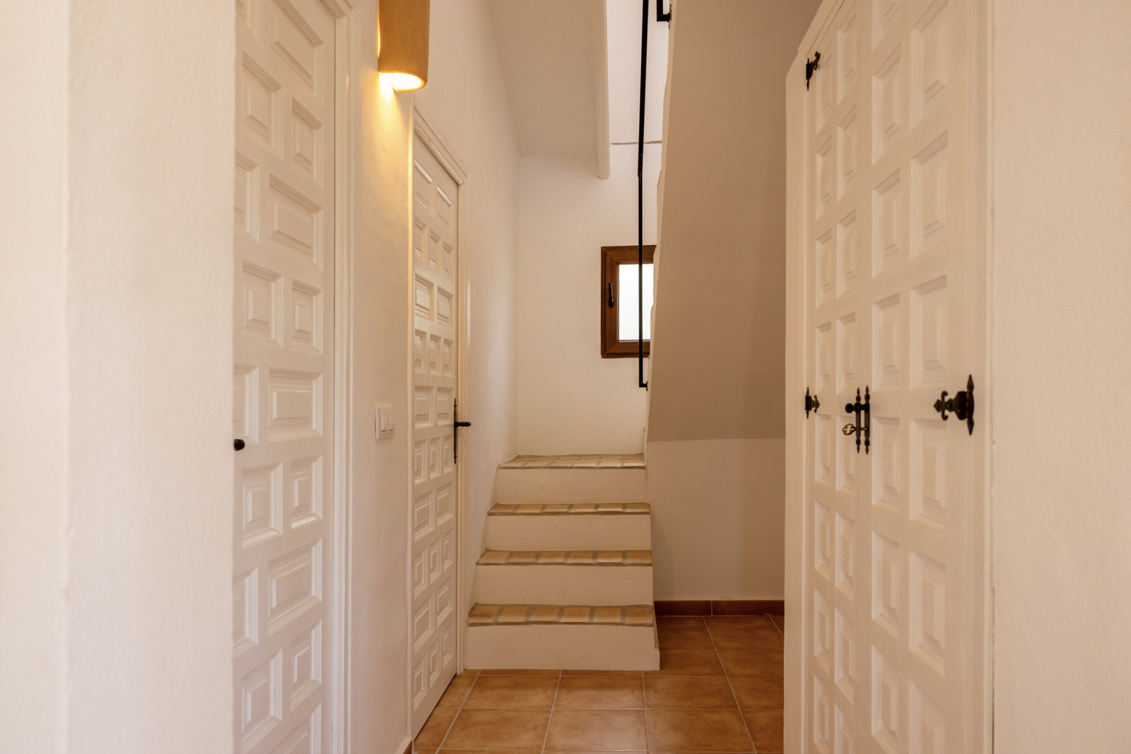 Hallway detail with tiled stairs and white wooden doors featuring a geometric design.