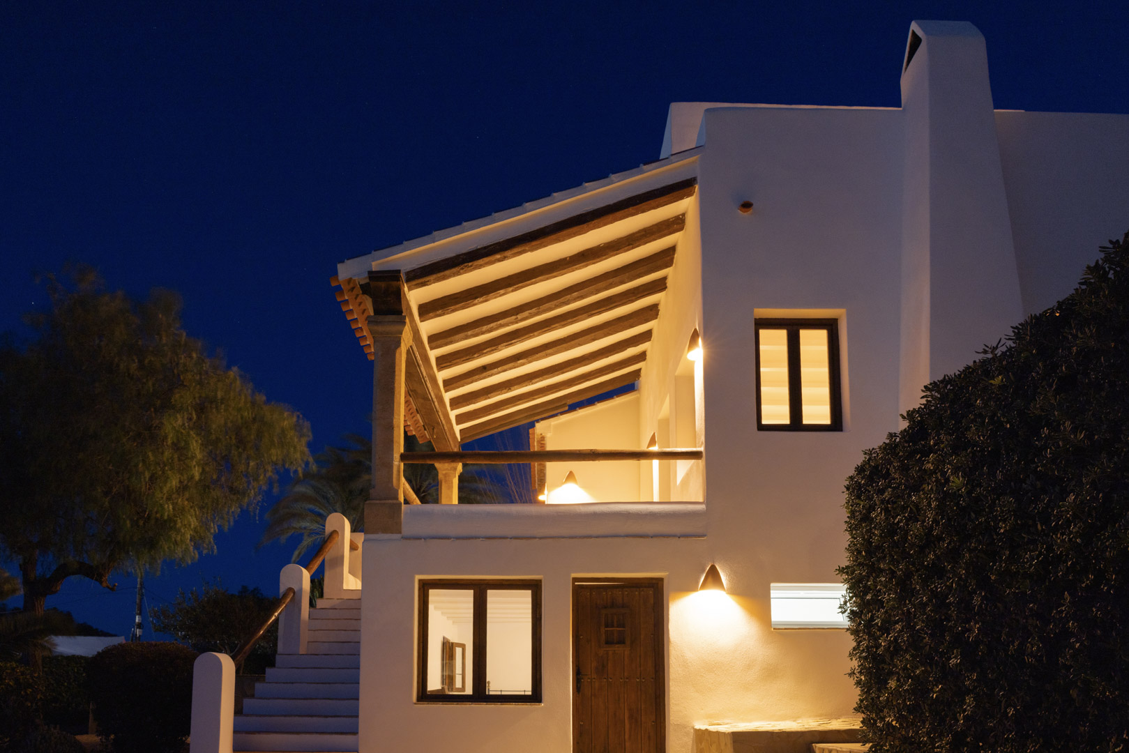 Illuminated villa facade in Tosalet, Jávea. Mediterranean architecture with covered terrace and wooden details.