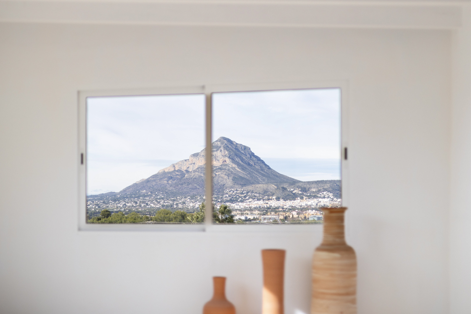 Interior view with ceramic vases and a window framing a mountain vista.