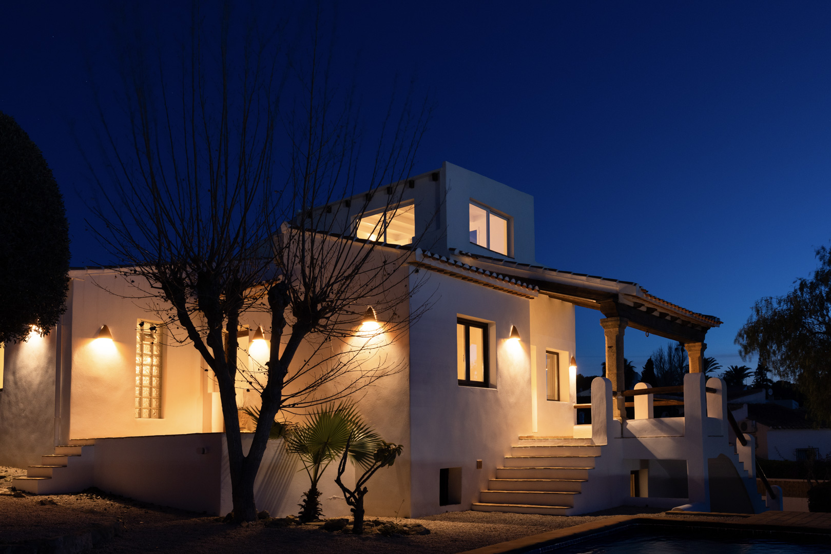 Night view of the villa featuring an illuminated white facade and stone details on the porch.