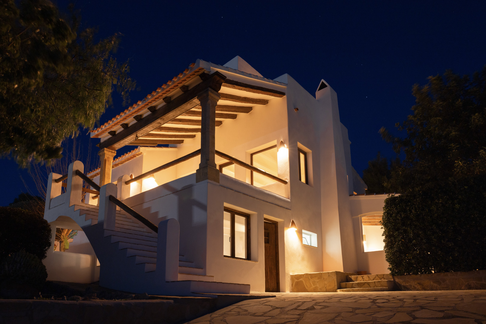 Night view of villa in Tosalet, Jávea. Mediterranean architecture with covered terrace, warm lighting, and stone details.