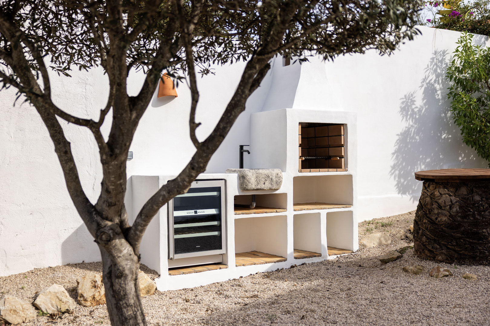 Outdoor kitchen detail featuring a built-in BBQ, stone sink, and wine fridge in Tosalet, Jávea.