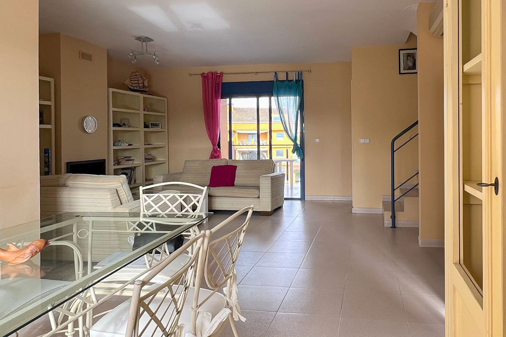 Bright living-dining area featuring a glass table, built-in shelving, and access to the terrace.