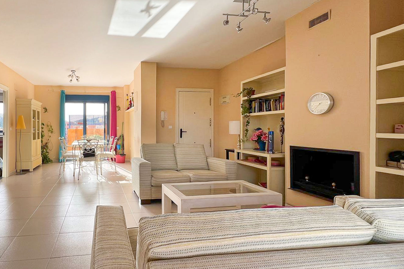 Bright living room featuring striped sofas, built-in shelving, and terrace access.