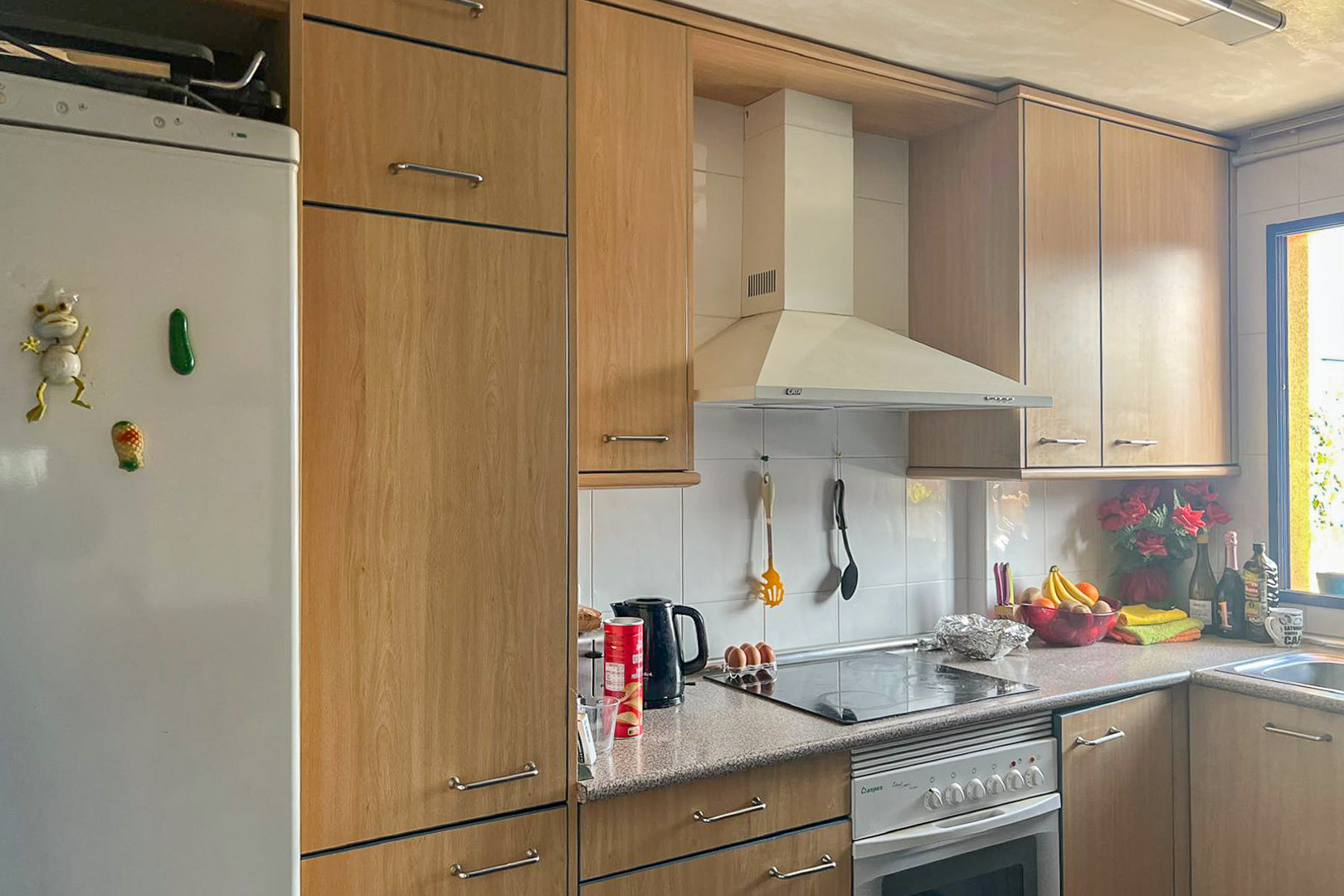Functional kitchen featuring light wood cabinets, white appliances, and a granite countertop.