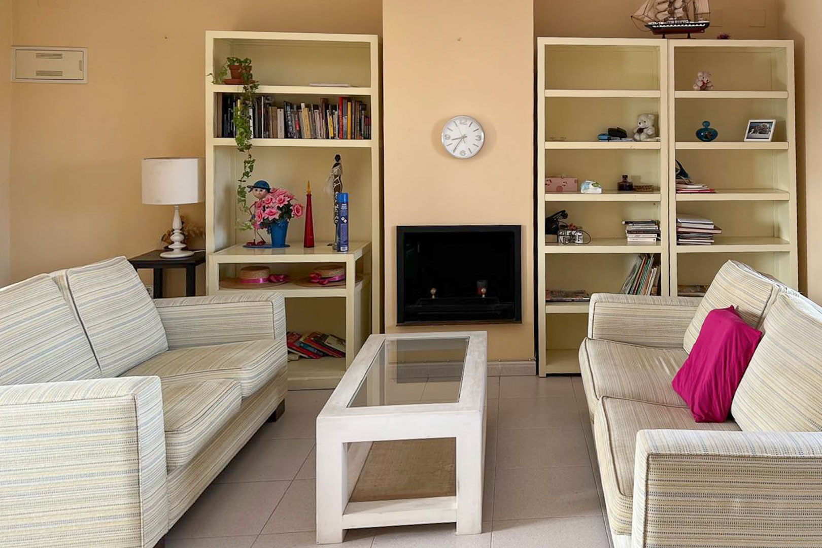 Living room featuring striped sofas, built-in shelving, and a decorative fireplace.