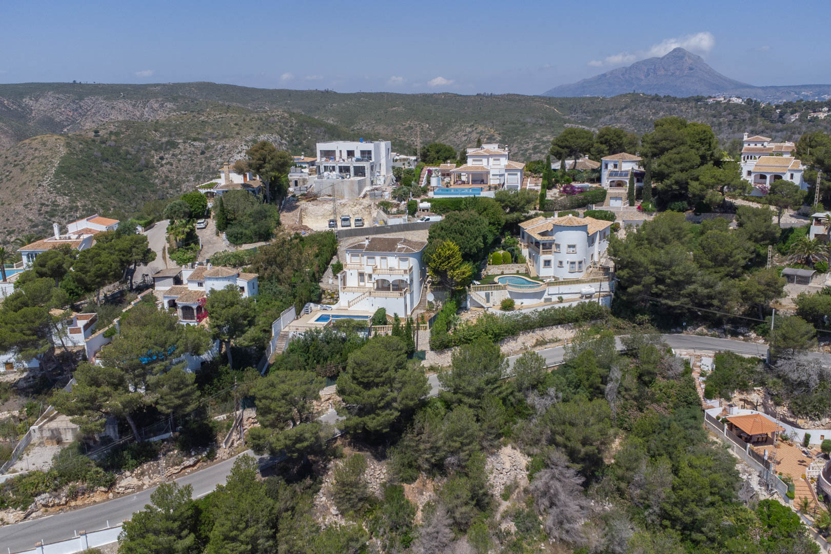 Aerial view of the Costa Nova residential area in Jávea, featuring Mediterranean villas, lush pine forests, and the Montgó mountain in the distance.