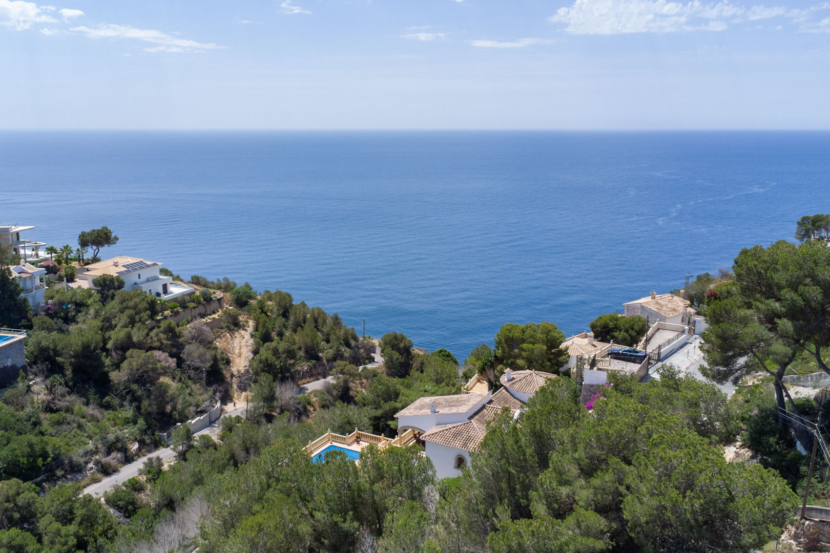 Elevated panoramic view of the Mediterranean Sea from Costa Nova, featuring dense pine forests and coastal villas near Granadella in Jávea.