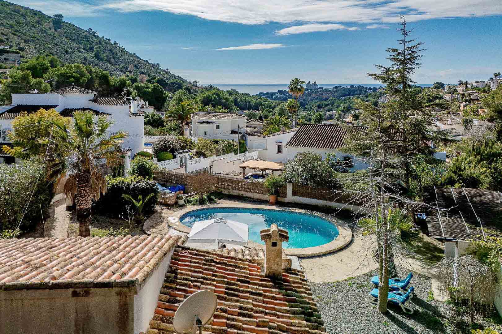 Elevated view featuring the kidney-shaped private pool and Mediterranean garden, offering clear sea views and a perspective of the surrounding coastal landscape.