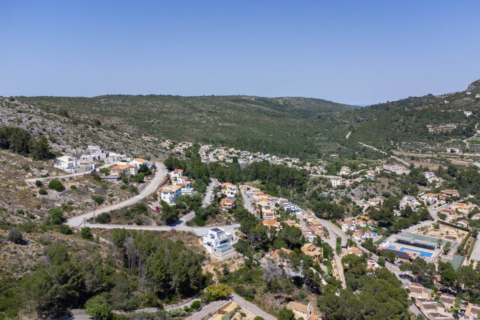 Panoramic aerial view of the VALL DE POP residential area in Alcalalí, highlighting the elevated plot positions and integration within the natural valley landscape.