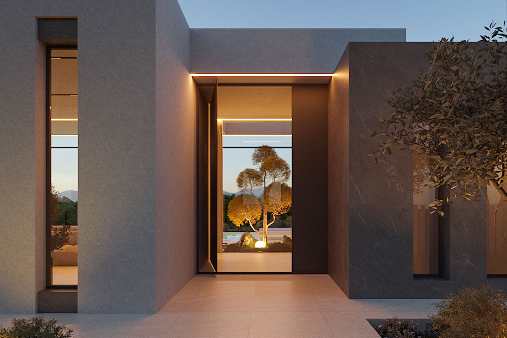 Minimalist main entrance featuring grey stone cladding, integrated LED strip lighting, and a clear view through to the illuminated Mediterranean garden.