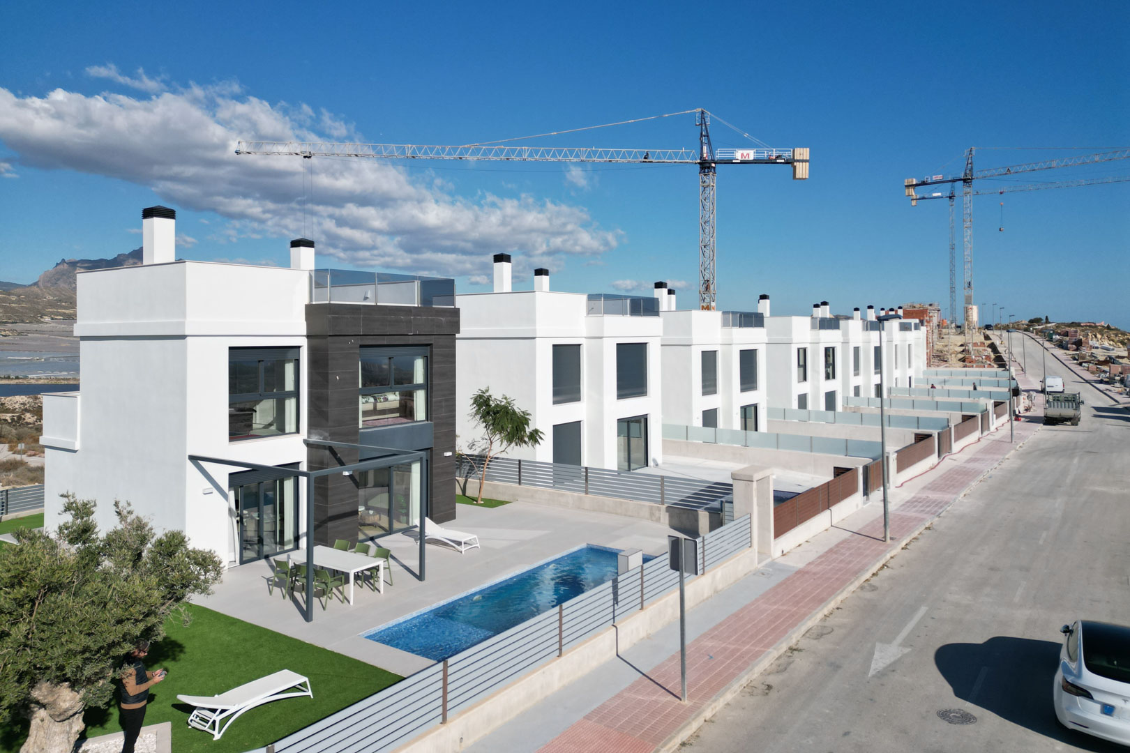 Aerial perspective of contemporary villas featuring white facades, dark stone accents, private pools, furnished terraces, and rooftop solariums.