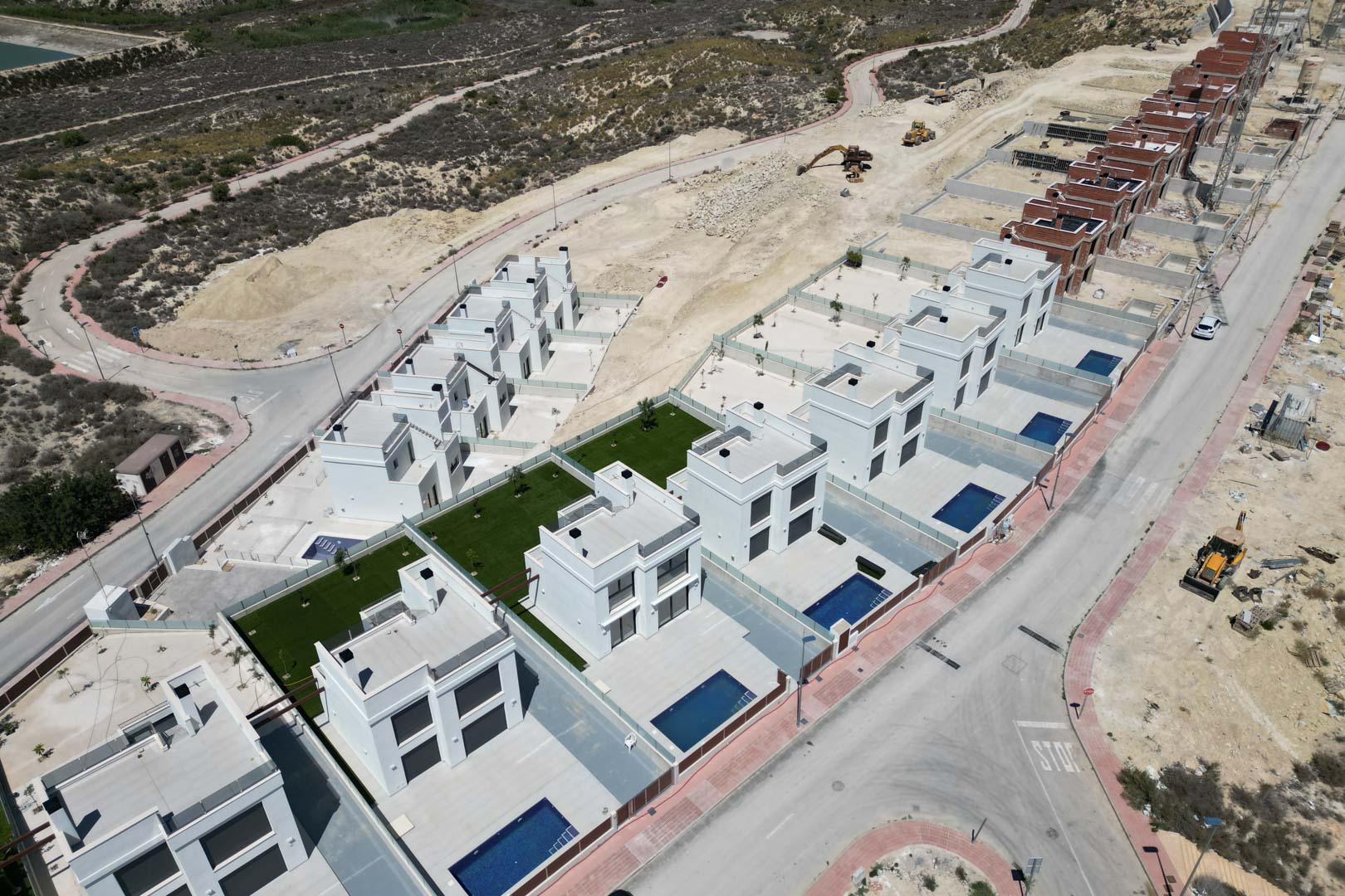 Aerial perspective of the development featuring modern cubic villas with private pools and terraces, set within an elevated landscape currently under construction.