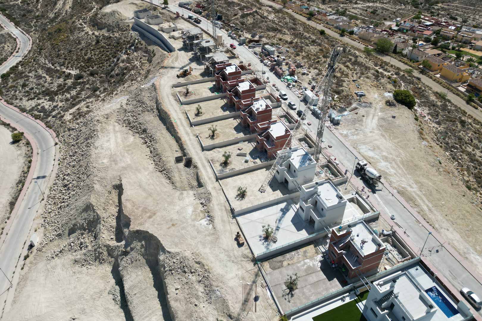 Aerial perspective of the villa development under construction, highlighting the elevated hillside plots and the progress of the contemporary structures.