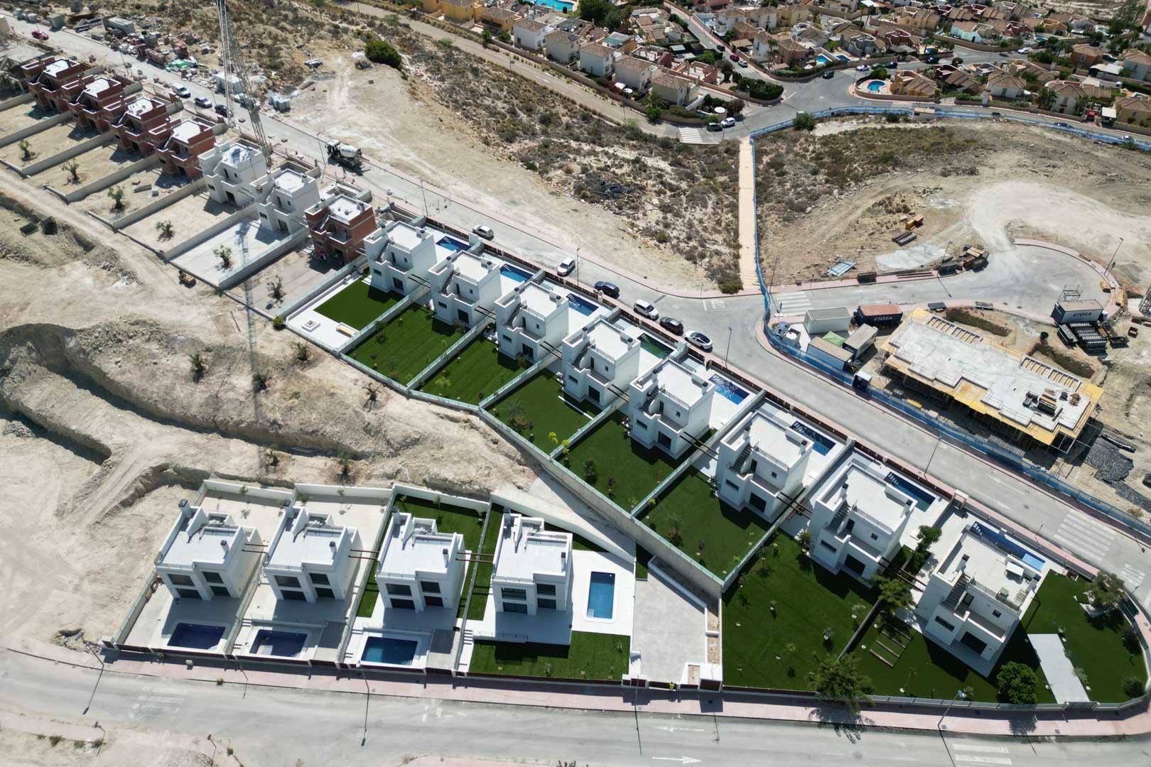Aerial view of a modern residential development featuring white villas with private pools and landscaped gardens on an elevated plot.
