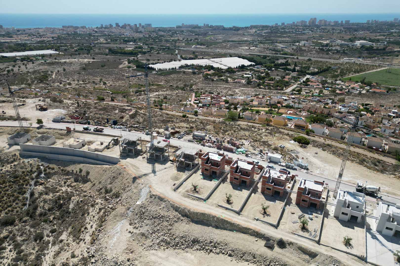 Aerial view of the villas under construction on a hillside, highlighting the elevated position and panoramic vistas towards the Mediterranean Sea and coastline.