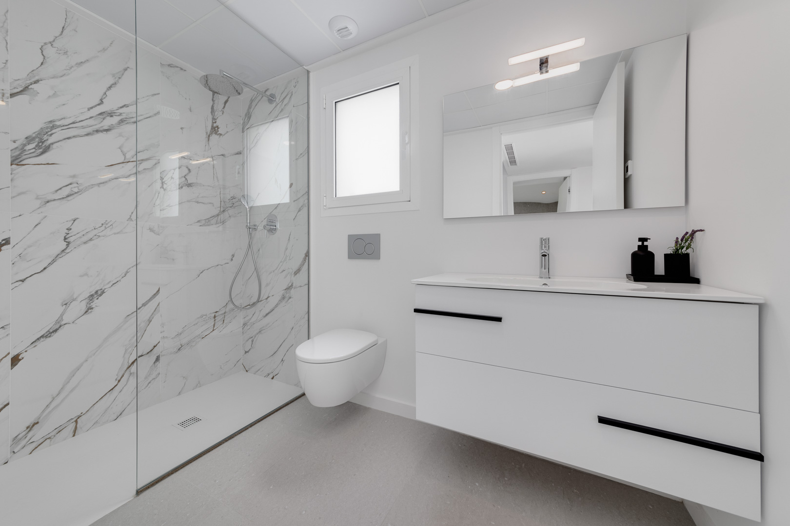 Contemporary bathroom featuring a walk-in shower with marble-effect porcelain tiles, a wall-hung toilet, and a floating white vanity with black accents.