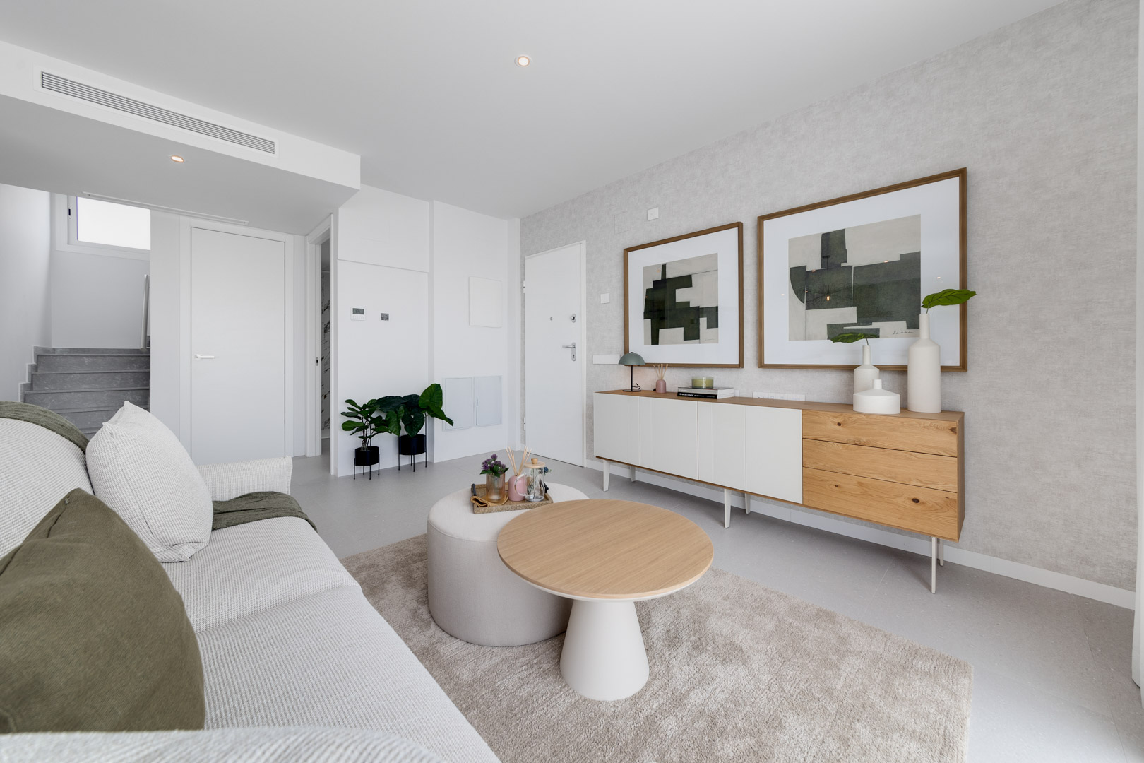 Contemporary living area featuring a minimalist sideboard, abstract art, and a comfortable seating arrangement with neutral tones and natural wood accents.
