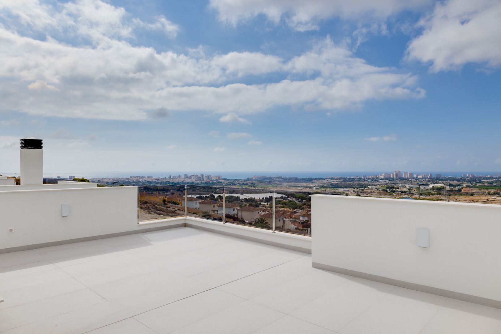 Upper terrace featuring large-format porcelain tiling, glass balustrades, and expansive panoramic views of the coastline and the Mediterranean Sea.
