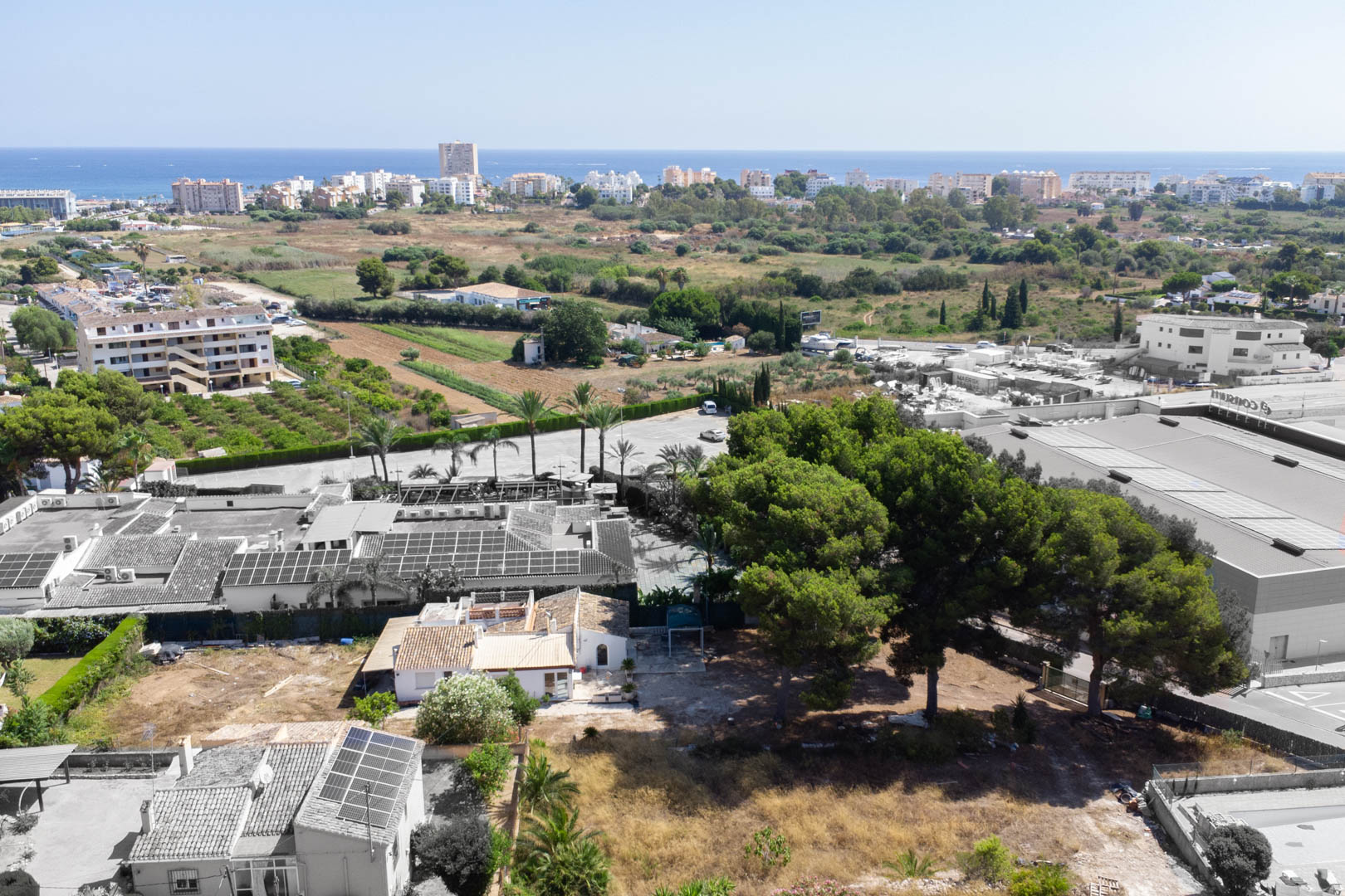Aerial view of the 2,600 m² plot in Jávea, featuring the existing villa, mature pine trees, and clear proximity to the Mediterranean coast.