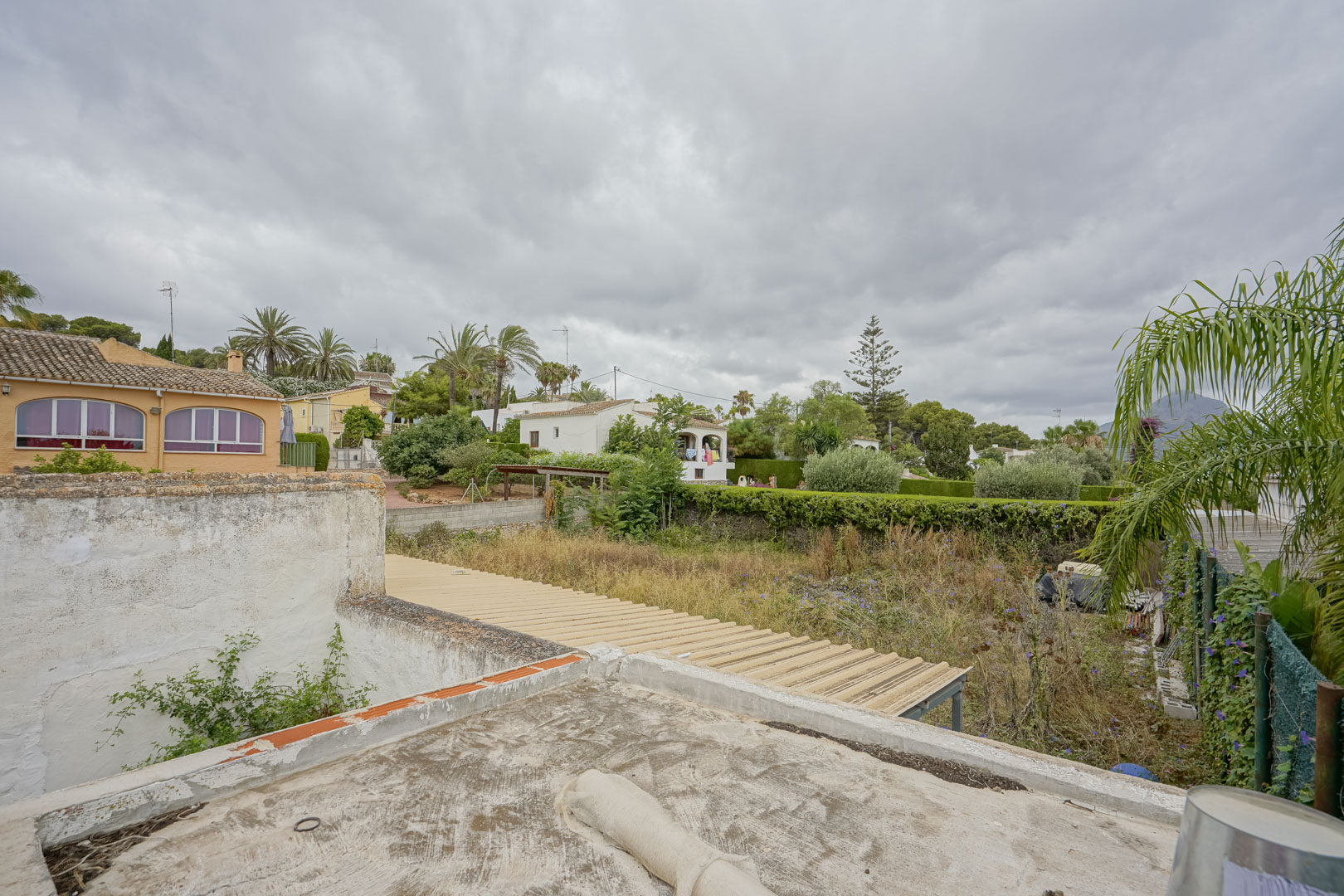 Elevated perspective of the 2,600 m² plot showcasing its scale and natural vegetation, bordered by residential villas with the Montgó mountain in the distance.