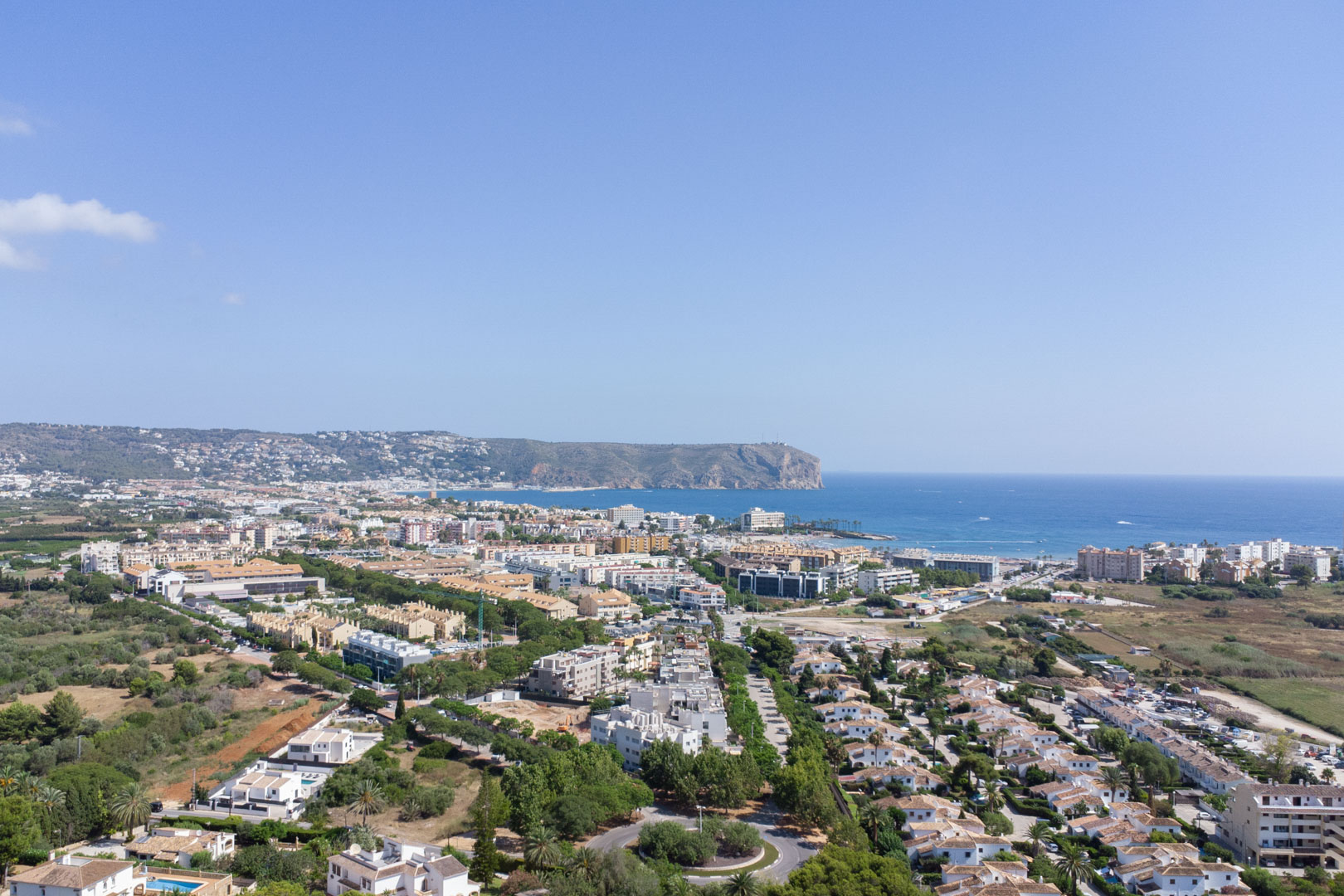 Panoramic aerial view of Jávea showcasing the proximity to the Mediterranean Sea and the iconic Cabo de San Antonio headland under a clear sky.
