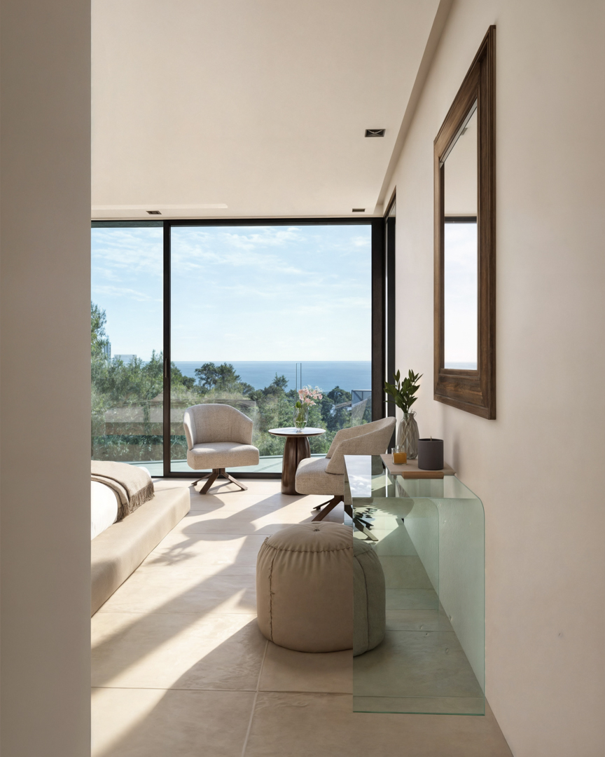 Bedroom featuring floor-to-ceiling glass doors with Mediterranean views, a seating area with swivel armchairs, and a minimalist glass console table over neutral tiling.