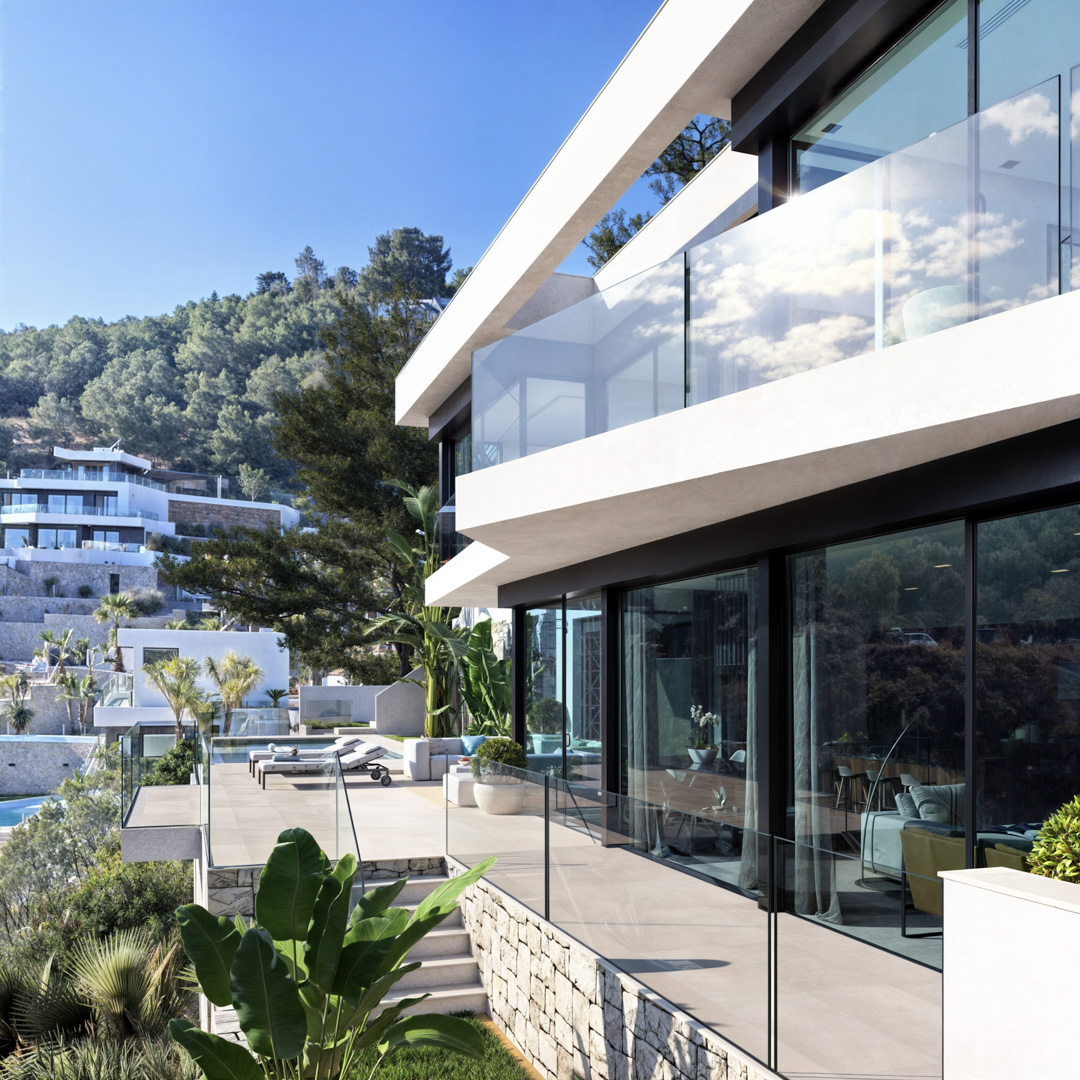 Exterior view featuring white cantilevered terraces, frameless glass balustrades, and floor-to-ceiling windows. Natural stone walls and tropical landscaping frame the outdoor lounge.
