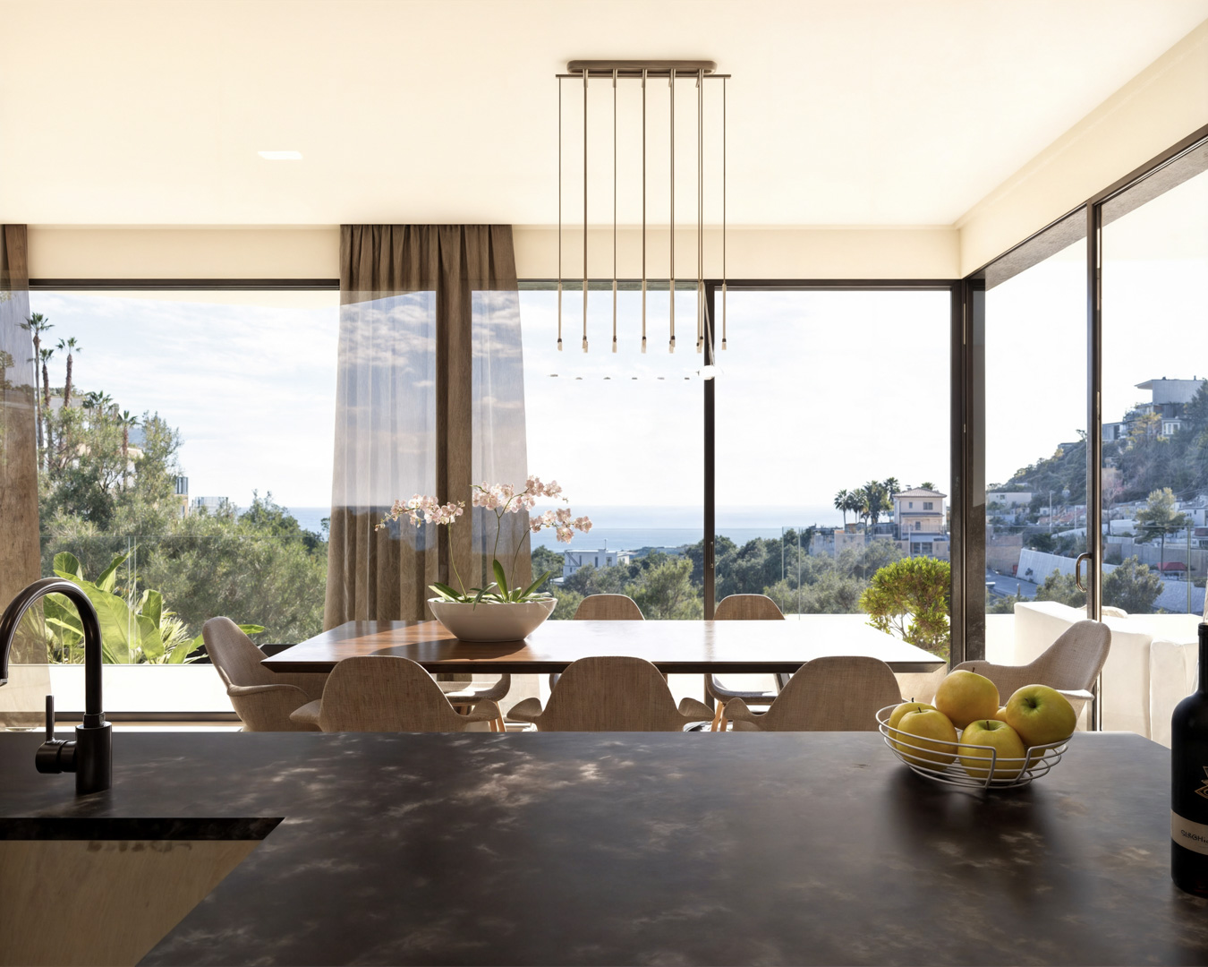 Integrated dining area featuring a wooden table, designer pendant lighting, and floor-to-ceiling windows offering panoramic views of the Mediterranean Sea.