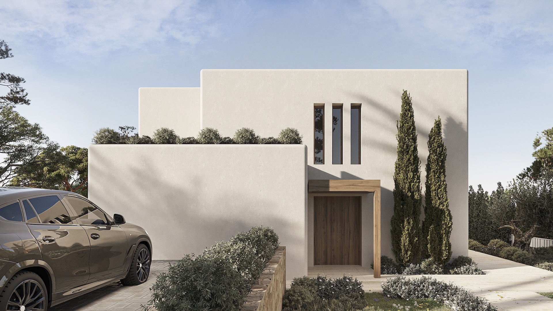 Ibicencan-style main facade featuring textured white walls, a wooden entrance door under a matching lintel, and narrow vertical windows. The driveway includes stone paving and cypress trees.