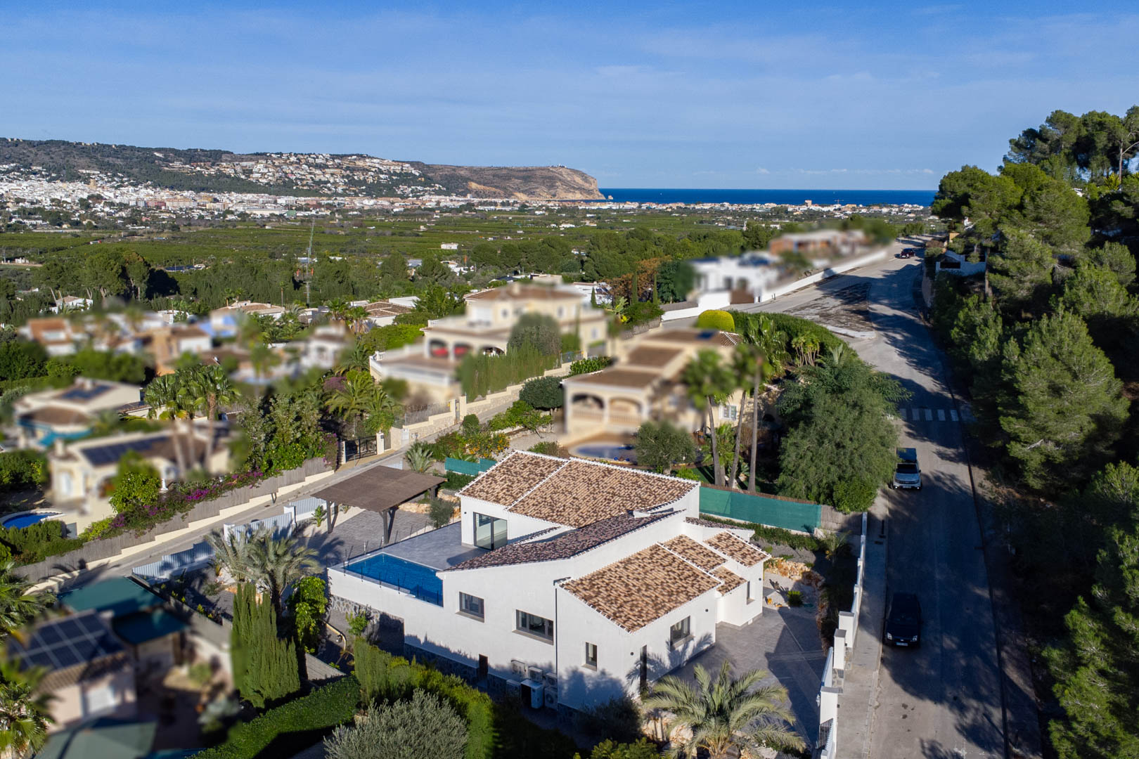 Aerial view of a modern villa with pool in Jávea, surrounded by gardens and overlooking the sea.