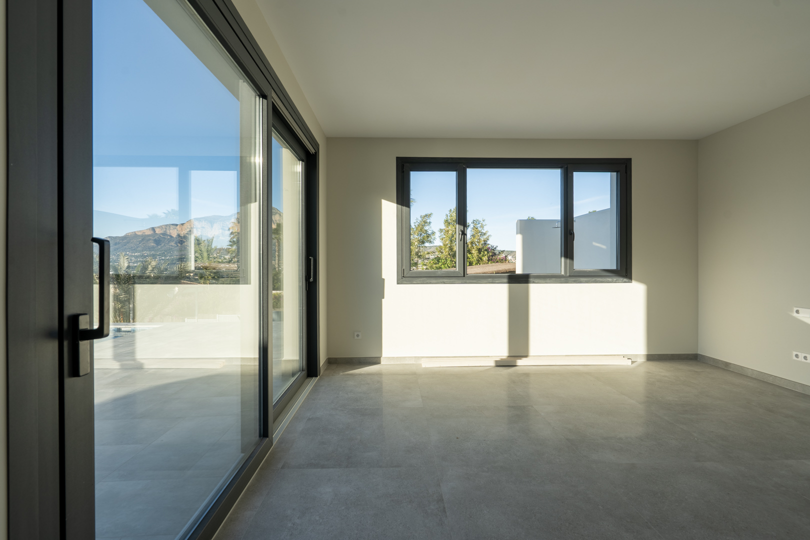 Bright interior space featuring gray tile flooring, expansive sliding glass doors, and exterior views.