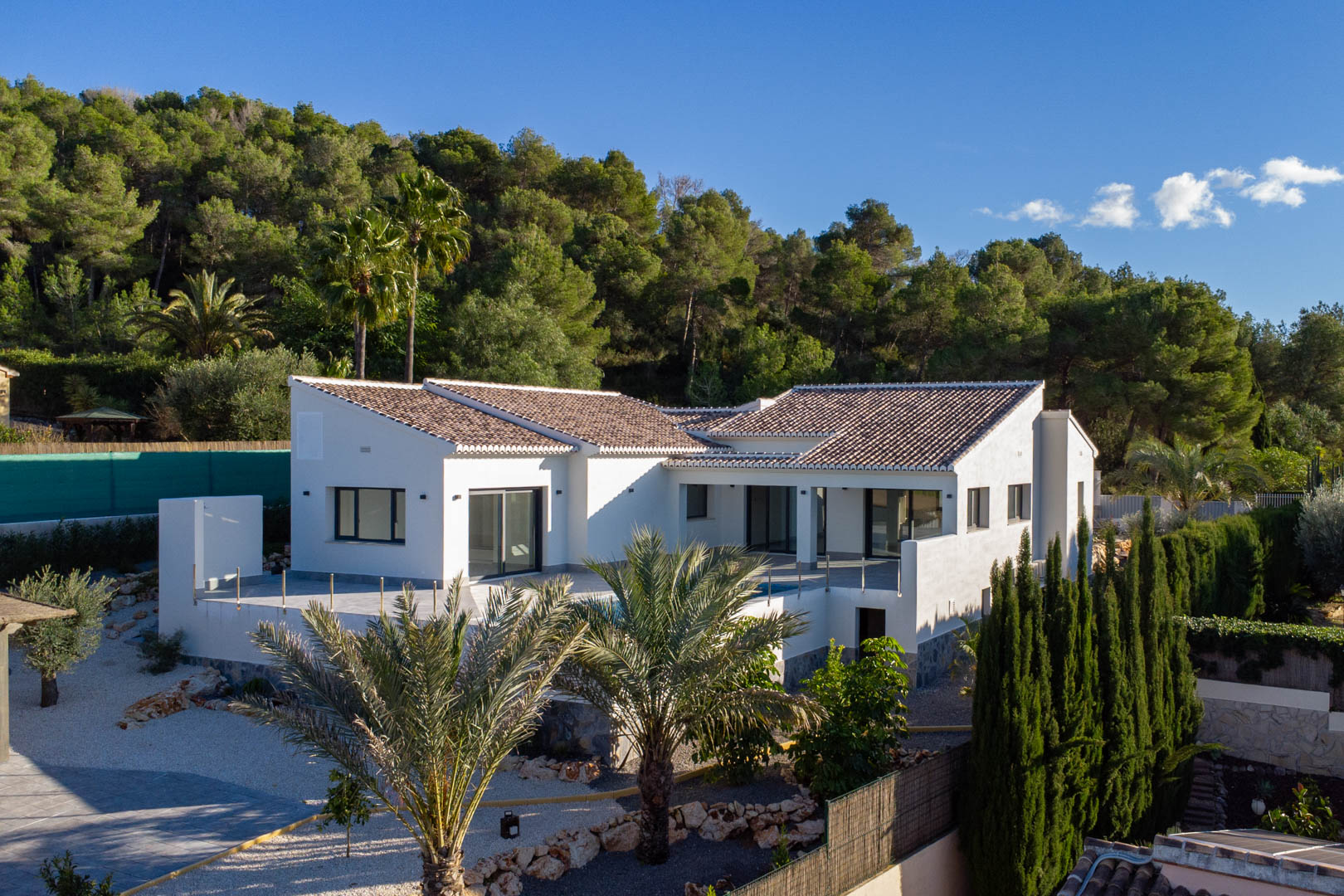 Exterior view of the new villa in Jávea, highlighting its modern design and private pool surrounded by lush greenery.