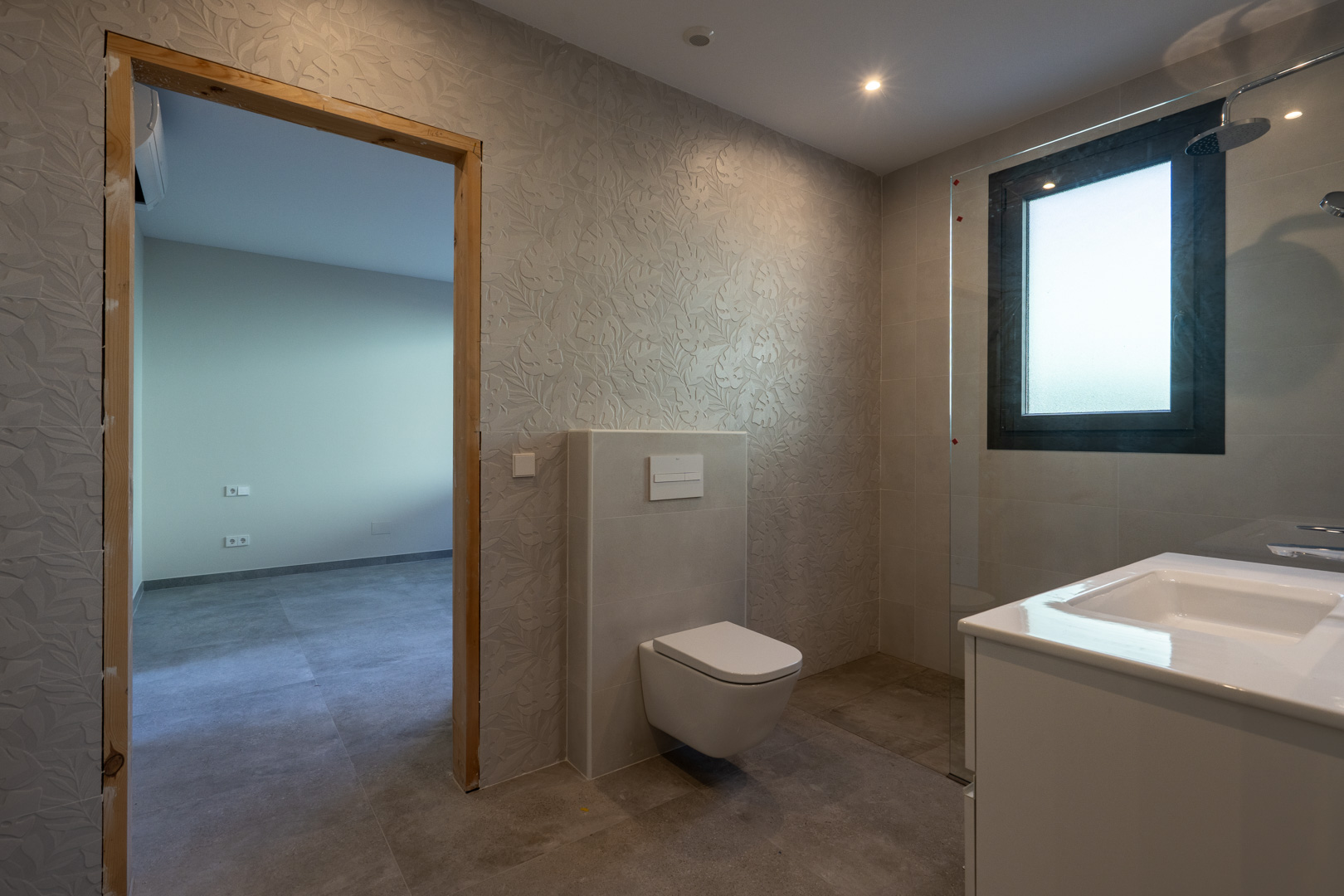 Modern bathroom detail with textured walls and glass-enclosed shower.