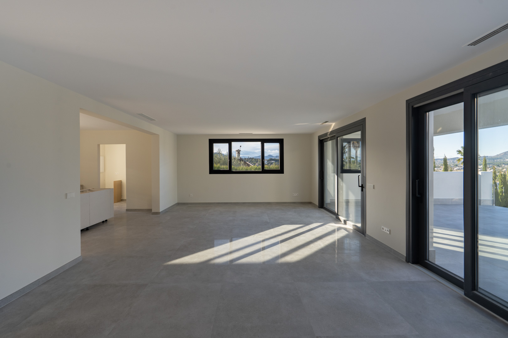 Spacious living room with tile flooring, panoramic window, and terrace access in Jávea.
