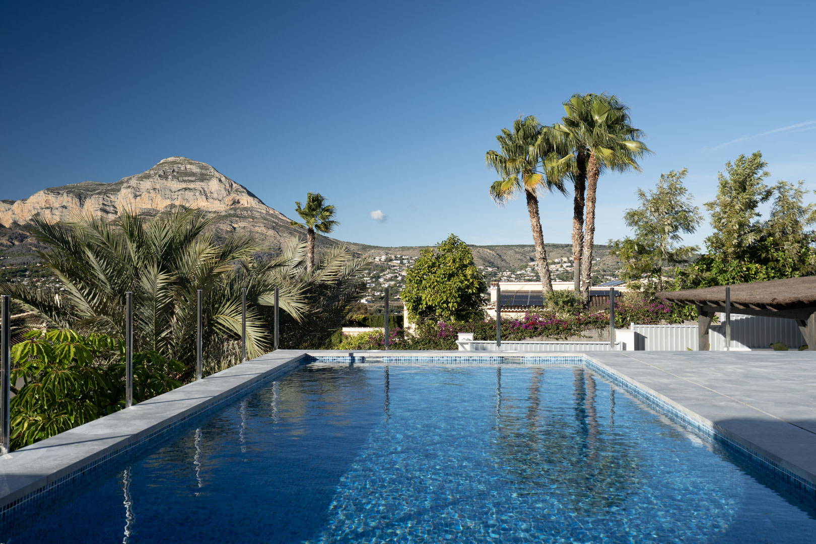 View of the private pool with blue mosaics, surrounded by greenery and with a majestic mountain in the background.