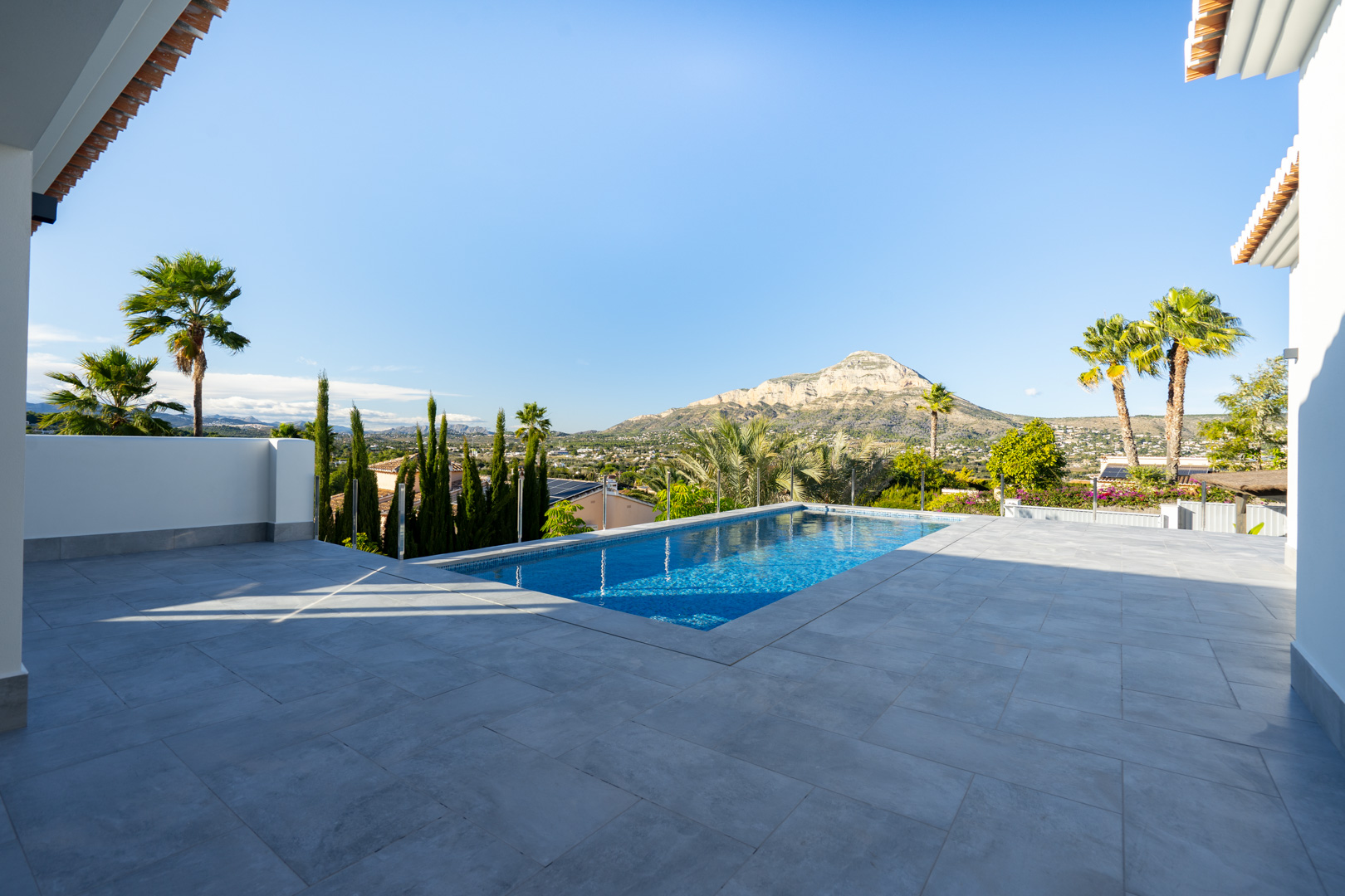 View of the private pool with gray tiling and mountainous landscape in Jávea.