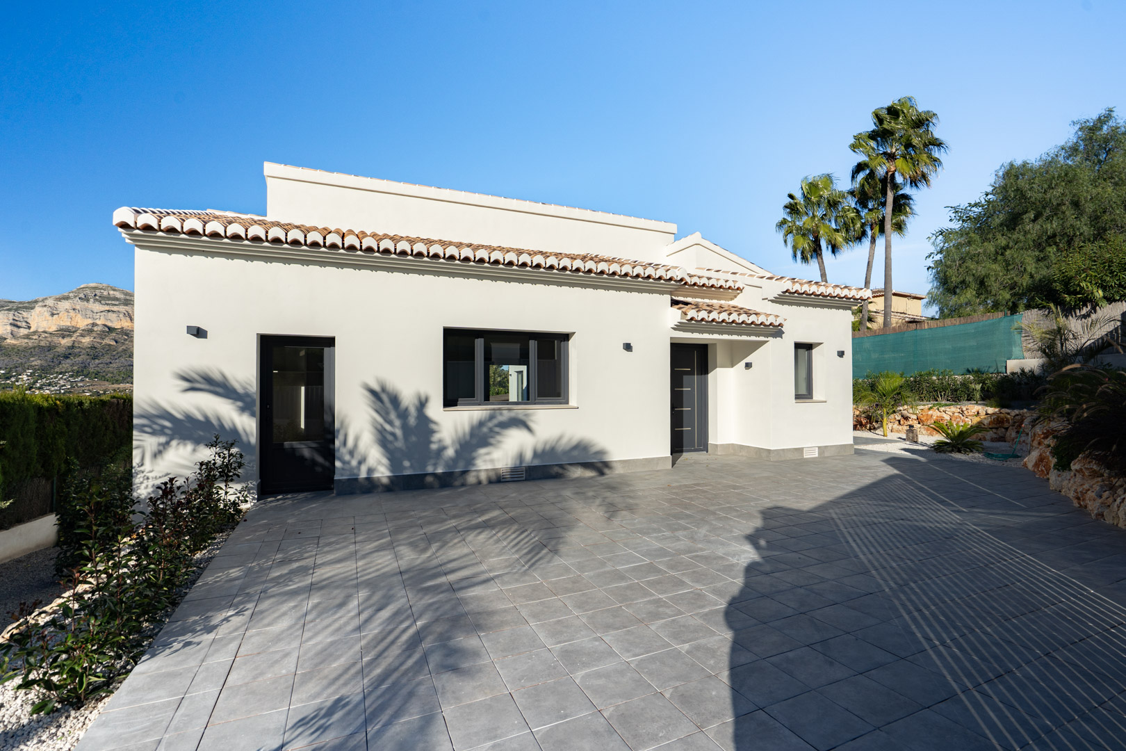 Villa exterior featuring a white facade, terracotta roof tiles, and gray tiled ground. Mountain views.