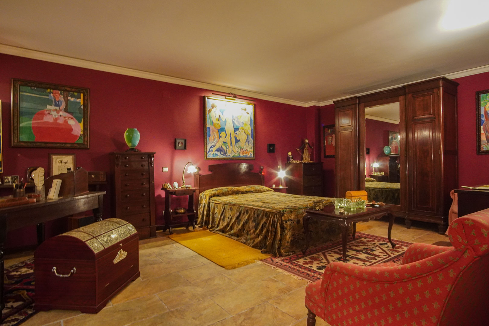 Classic bedroom featuring burgundy walls, dark wood antique furniture, natural stone flooring, and a large wardrobe with a central mirror.