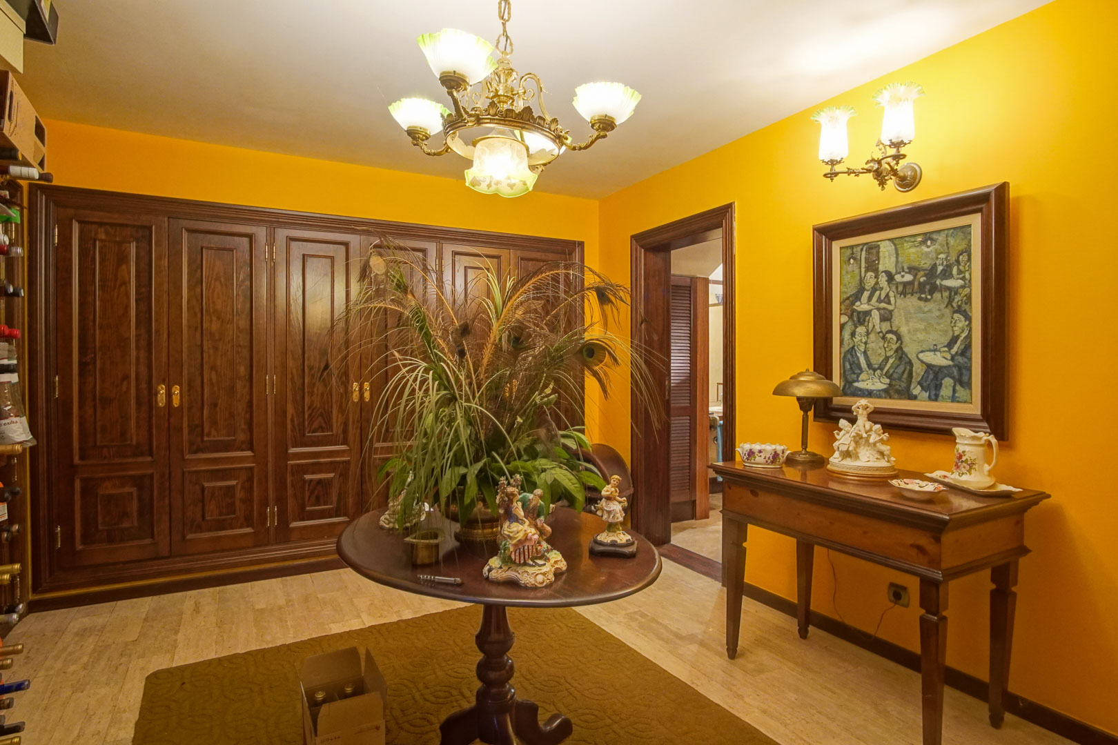 Entrance hall featuring mustard-colored walls, dark wood cabinetry, marble flooring, and classic furniture under ornate traditional chandeliers.
