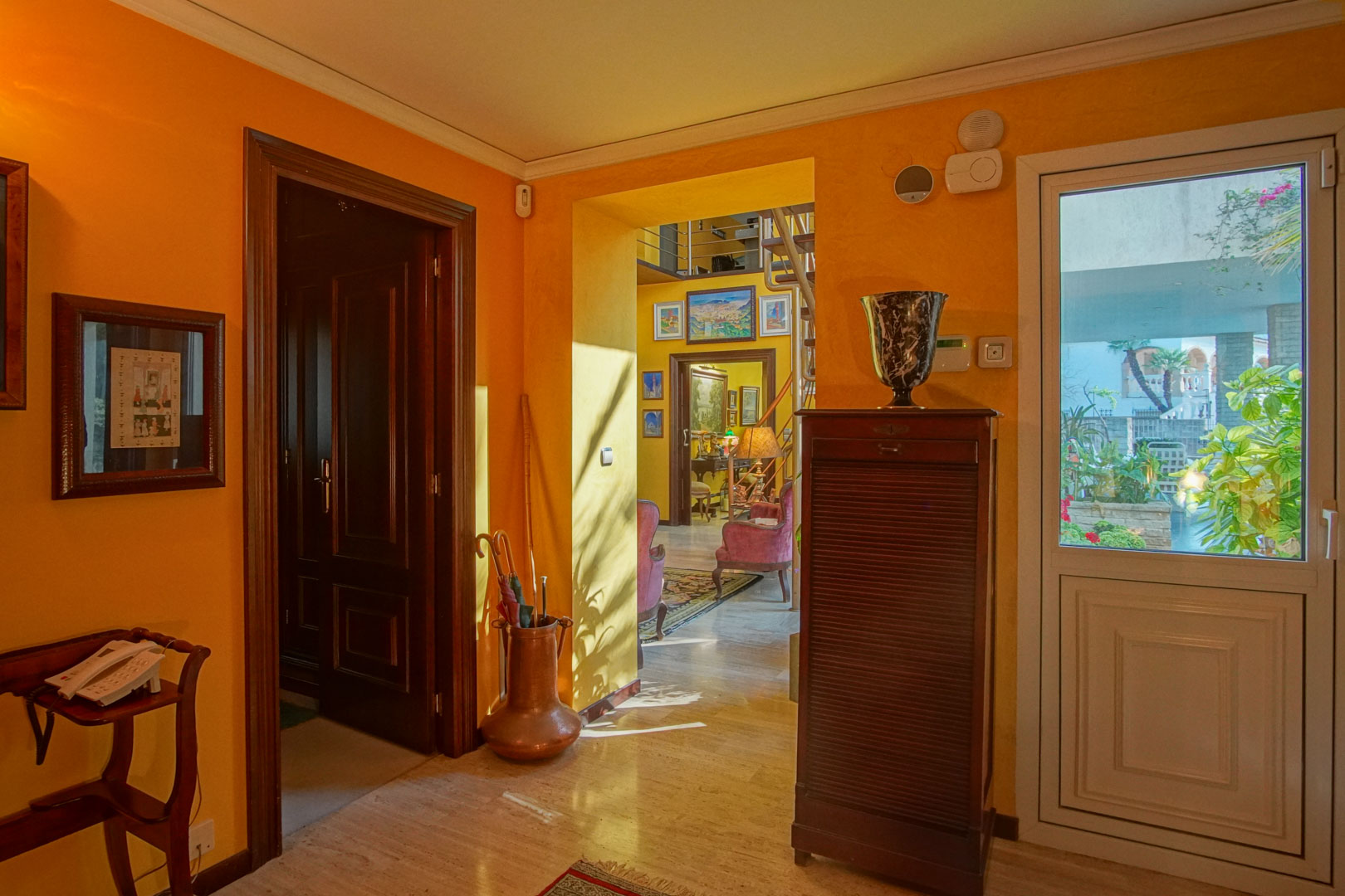 Entrance hall featuring polished marble floors, warm-toned walls, and dark wood joinery. It provides access to the living area with ample natural light.