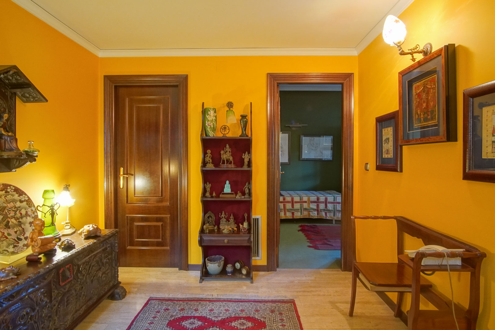 Hallway featuring marble flooring, mustard-colored walls, and solid dark wood doors, providing access to a bedroom with contrasting green walls.
