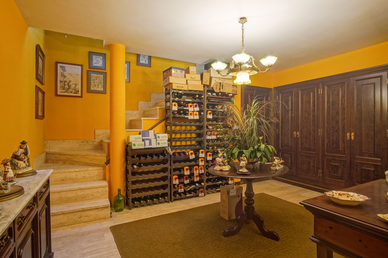 Lower-level wine cellar featuring marble flooring, dark wood cabinetry, and extensive bottle racks adjacent to a marble staircase.
