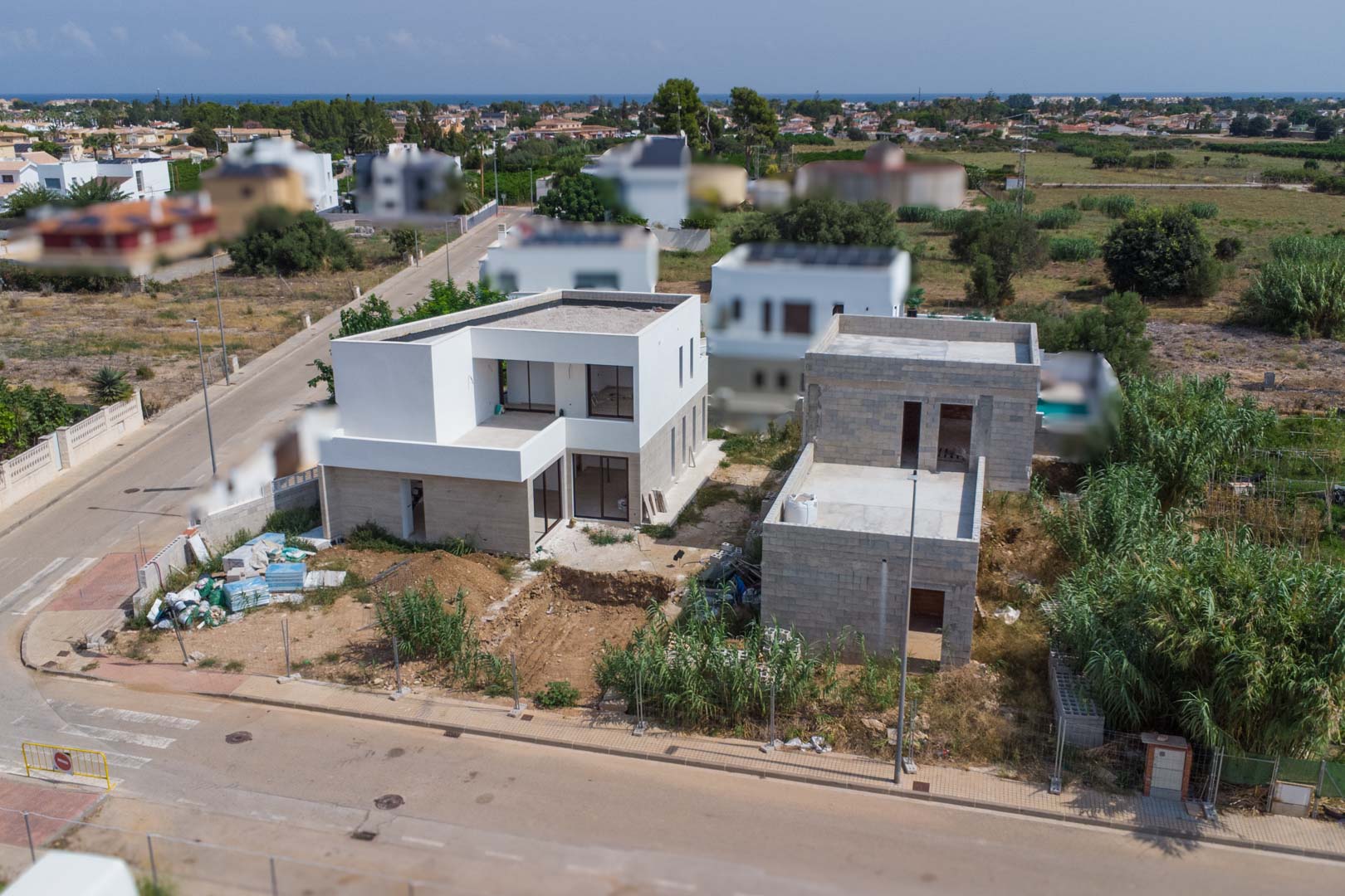 Aerial view of the residential project in El Vergel, featuring two modern villas under construction with white facades and clear views toward the Mediterranean coast.