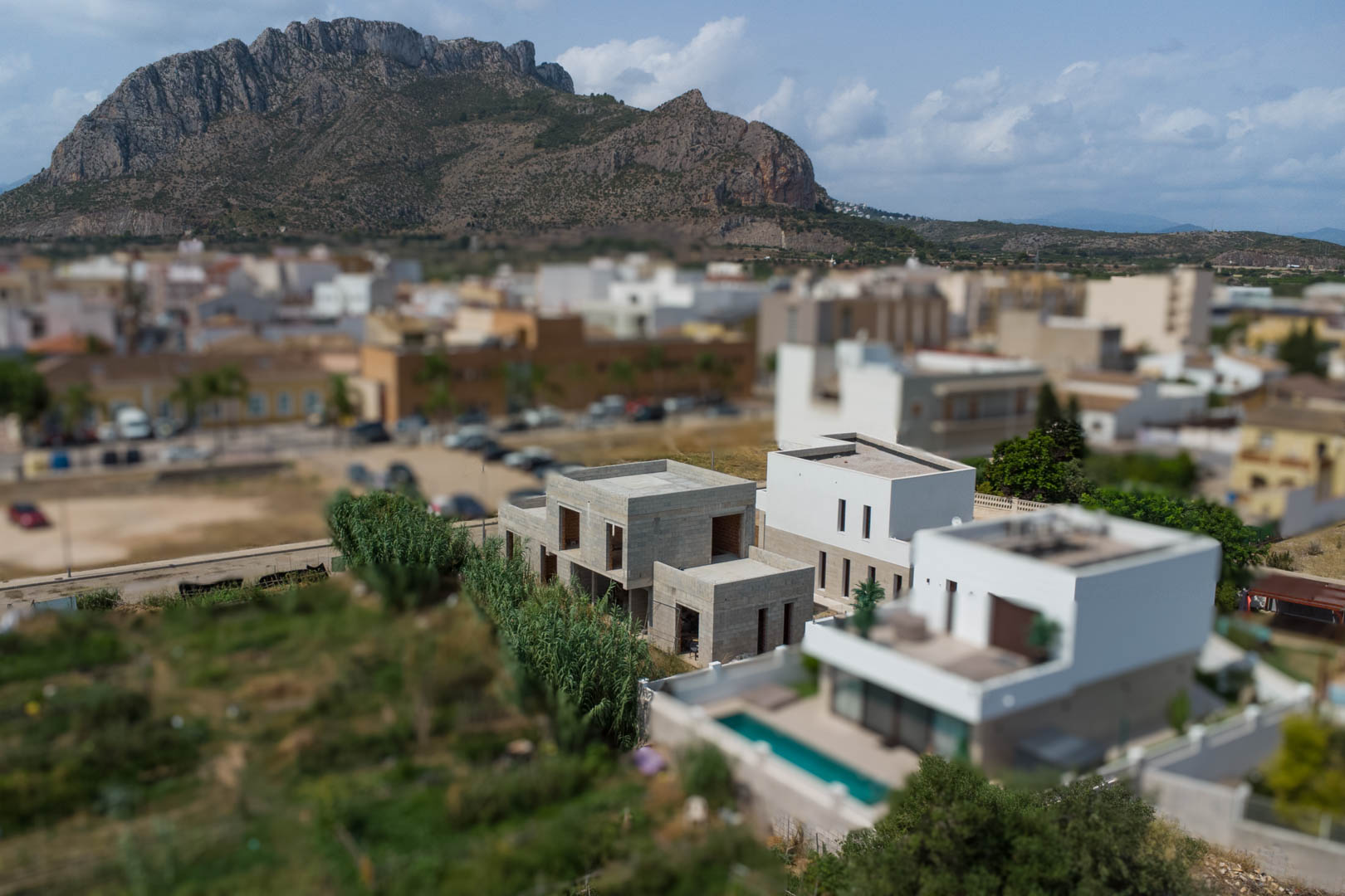 Elevated view of three modern villas under construction in El Vergel, featuring minimalist architecture and views of the Segaria mountain range.