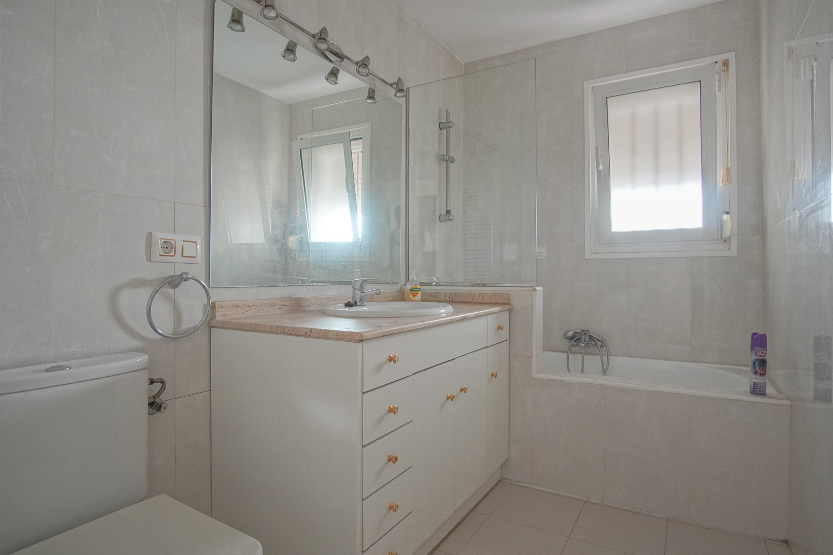 Full bathroom featuring a white vanity with marble countertop, integrated bathtub with glass screen, and natural light from a frosted window.